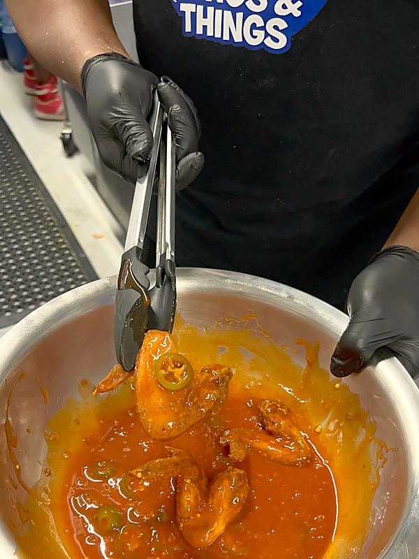 Cook tossing wings in buffalo sauce with jalapeños