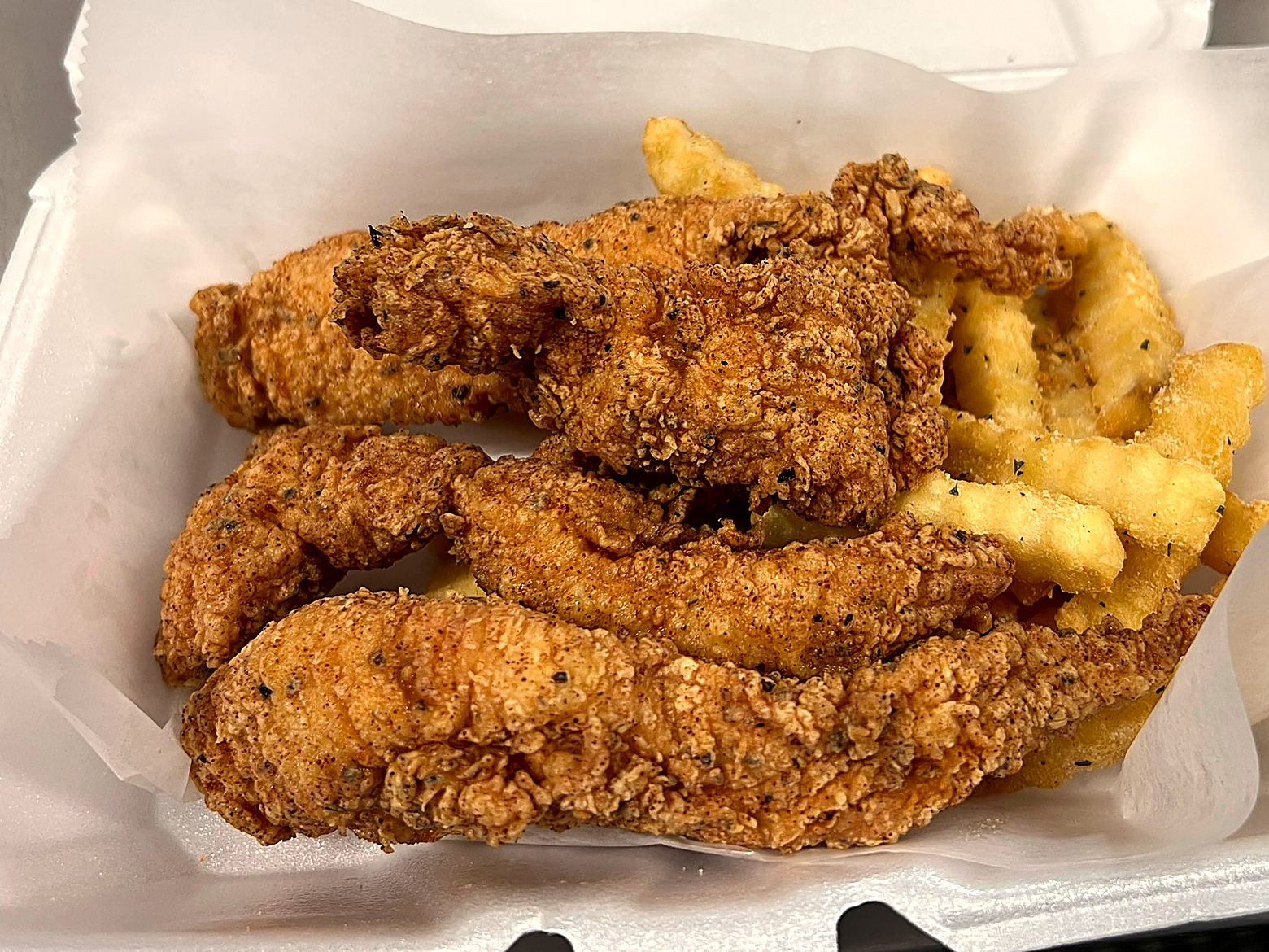 Hand breaded chicken tenders over crinkle fries