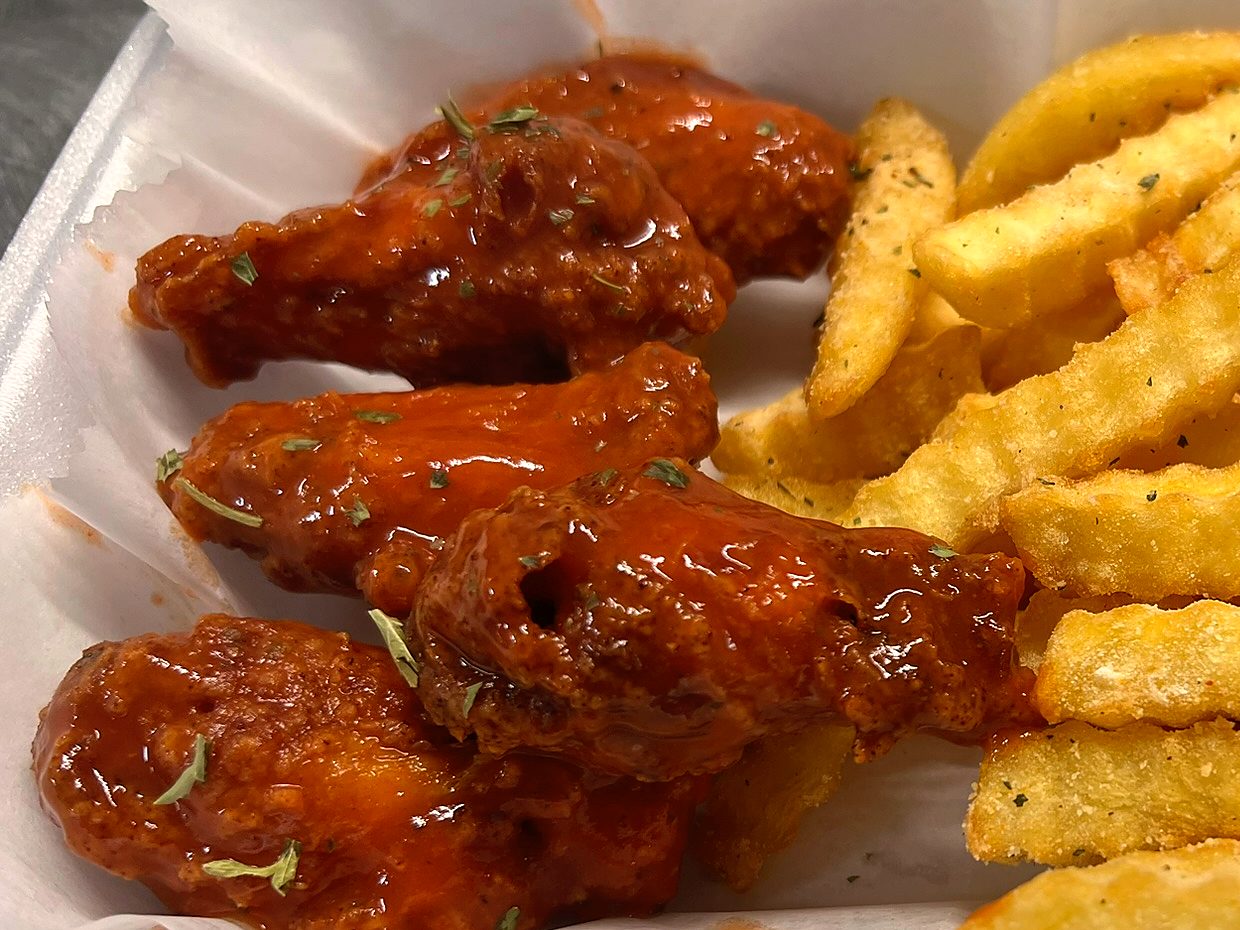Glossy buffalo wings beside seasoned crinkle fries