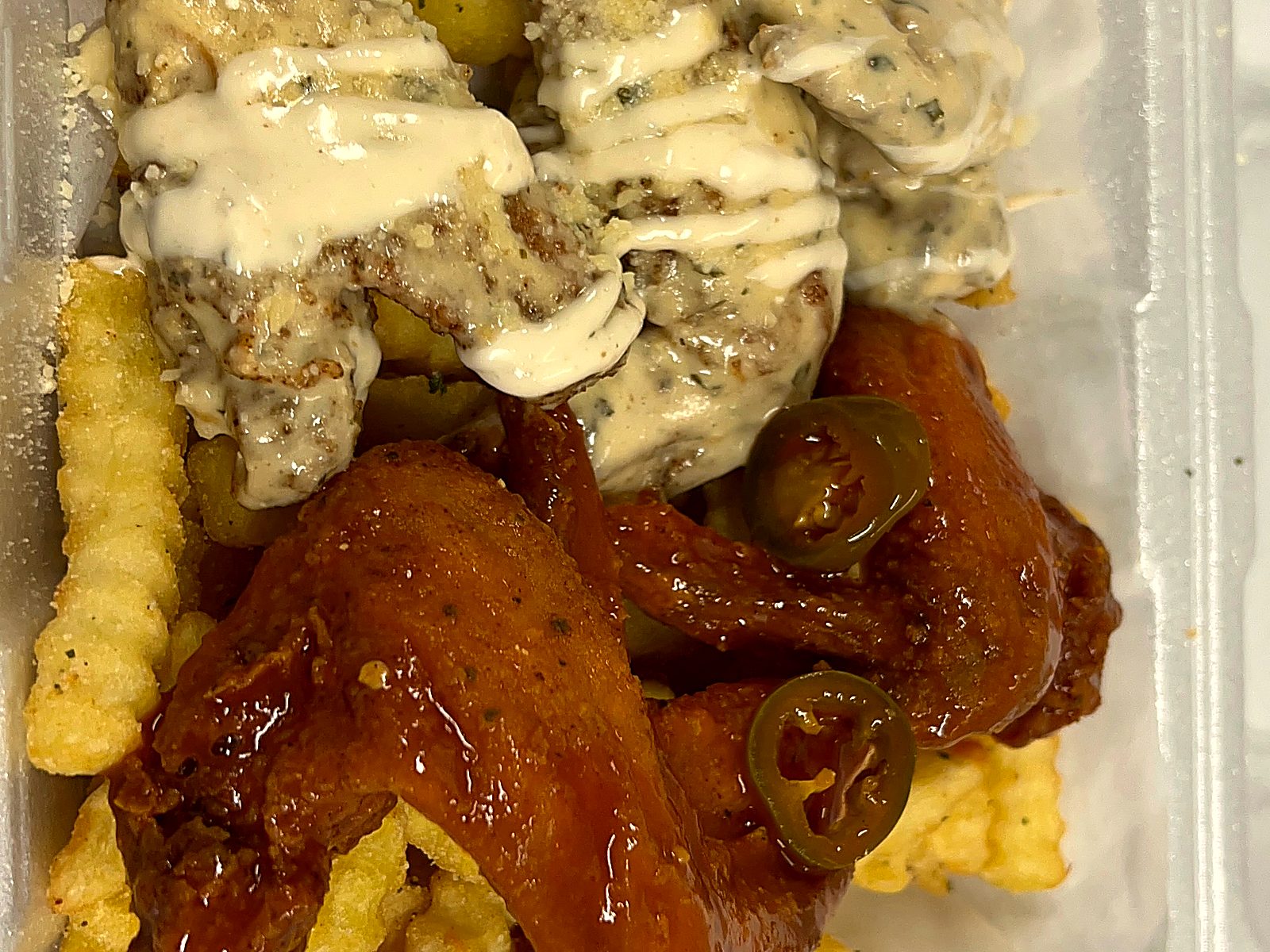 Whole wings in two sauces, garlic parmesan and buffalo with jalapeños, over crinkle fries